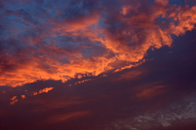 地表に斜めに侵入する日没直前の太陽の光の影響を強く受けた雲の写真